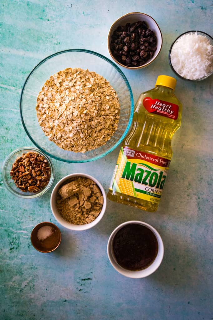 overhead shot of ingredients to make homemade granola on a teal blue background. 