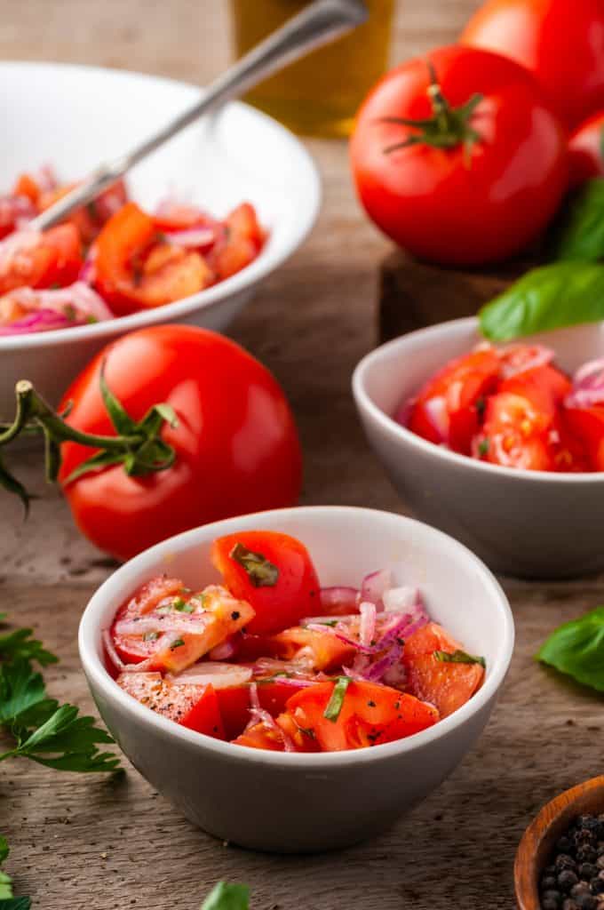 3 white bowls of tomato onion salad