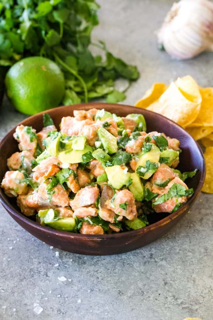 wood bowl of salmon ceviche on metal background