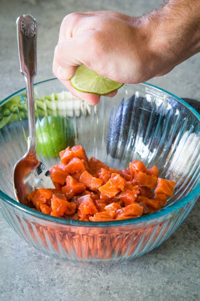 squeezing lime into bowl of salmon ceviche