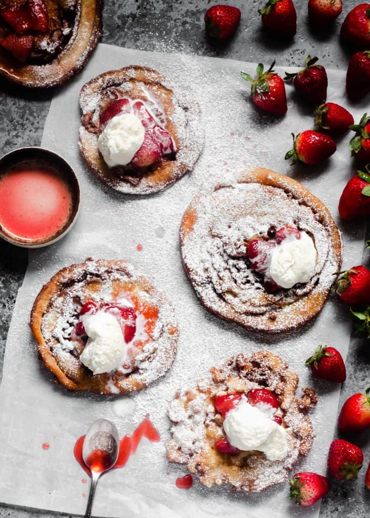 overhead shot of funnel cakes with strawberries and whipped cream