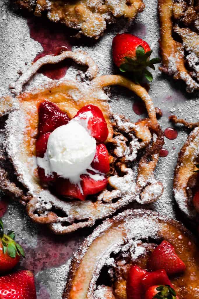 overhead shot of strawberry funnel cake with dollop of whipped cream