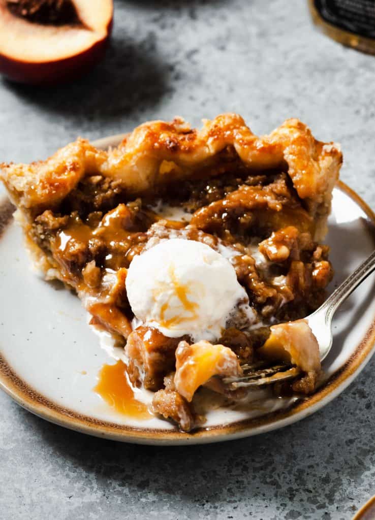 close up of slice of peach pie crumble with fork taking a bite