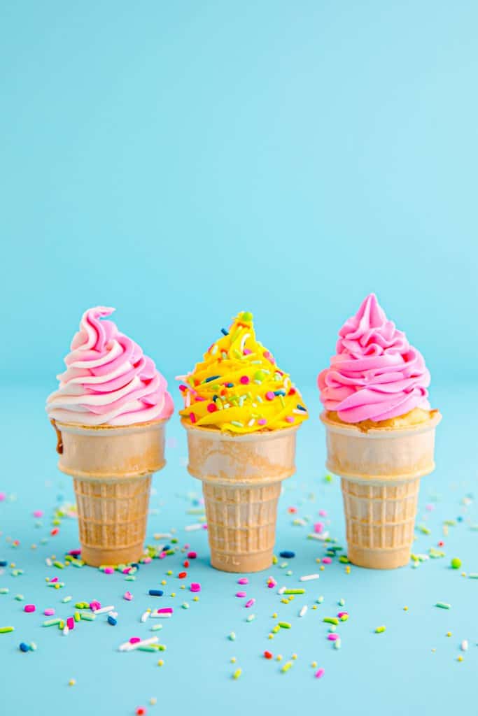 3 ice cream cone cupcakes with pink and yellow frosting