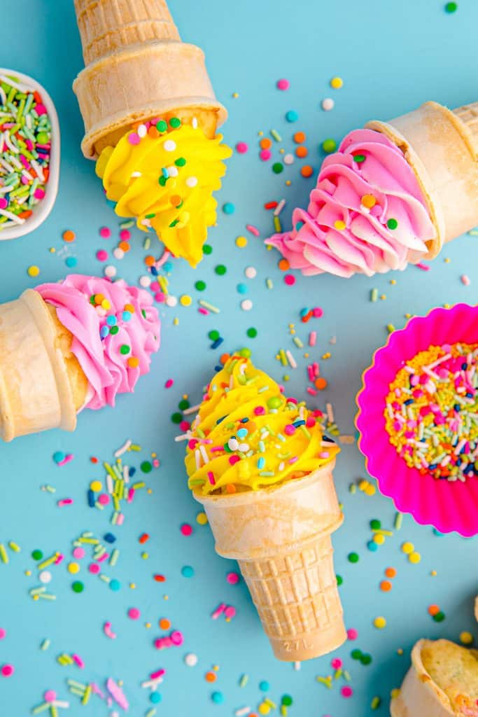 four ice cream cone cupcakes on their sides on blue background