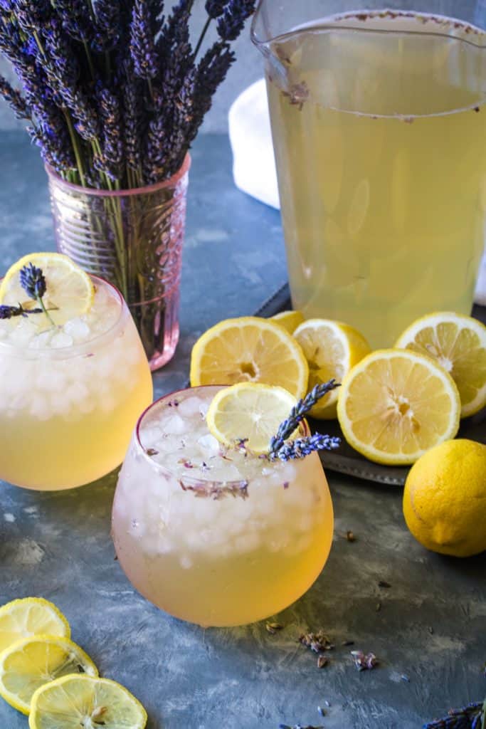 two glasses of lavender lemonade with bouquet of fresh lavender in background