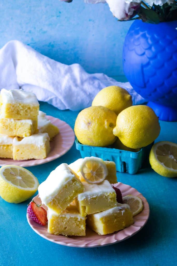 pink plates layered with lemon brownies on blue background