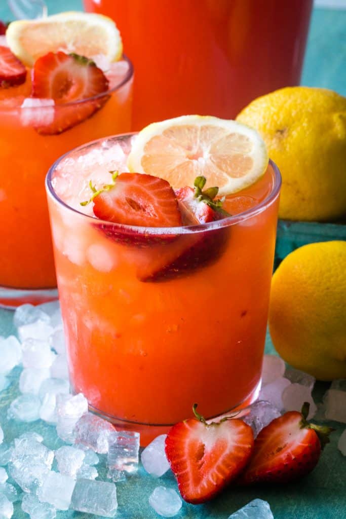 glasses of strawberry lemonade garnished with strawberries and lemons