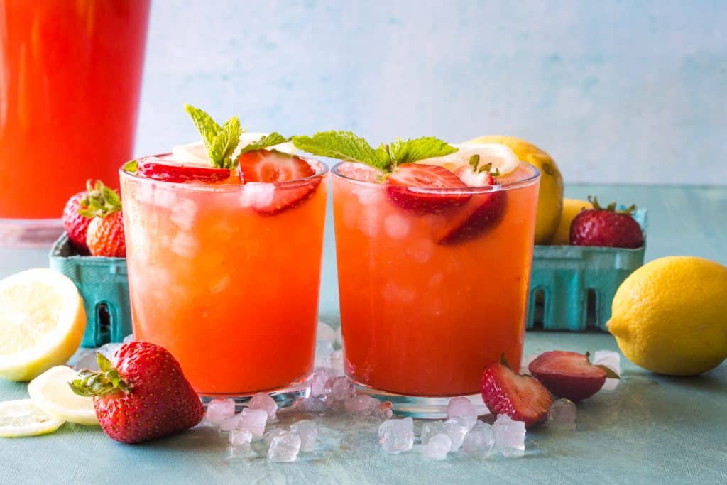 two glasses of strawberry lemonade on blue background