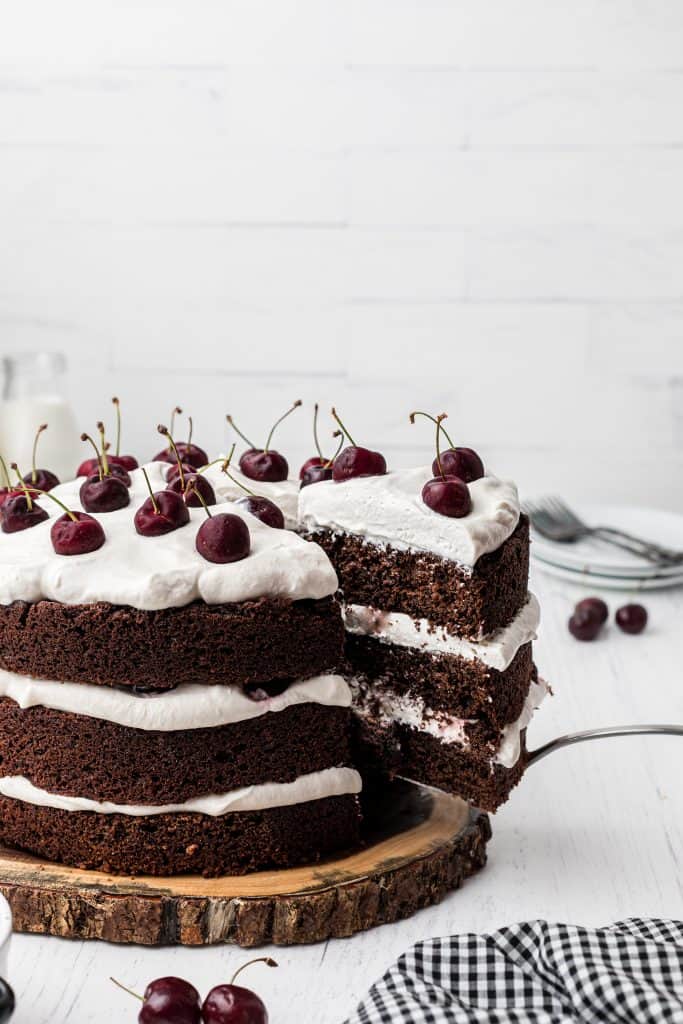 hand taking a slice of Black Forest cake on white background