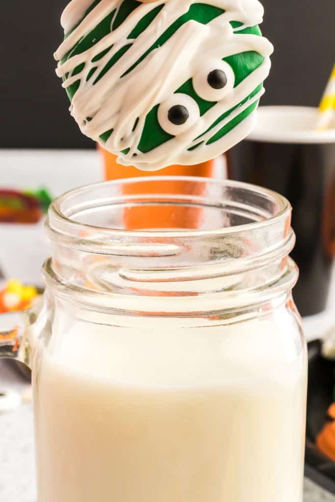 dipping the green mummy Oreo in a glass of milk