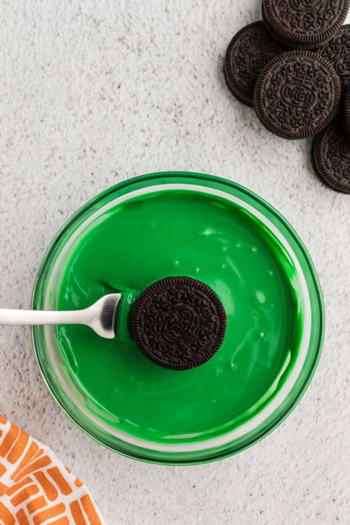 dipping the Oreo in the green melting chocolate