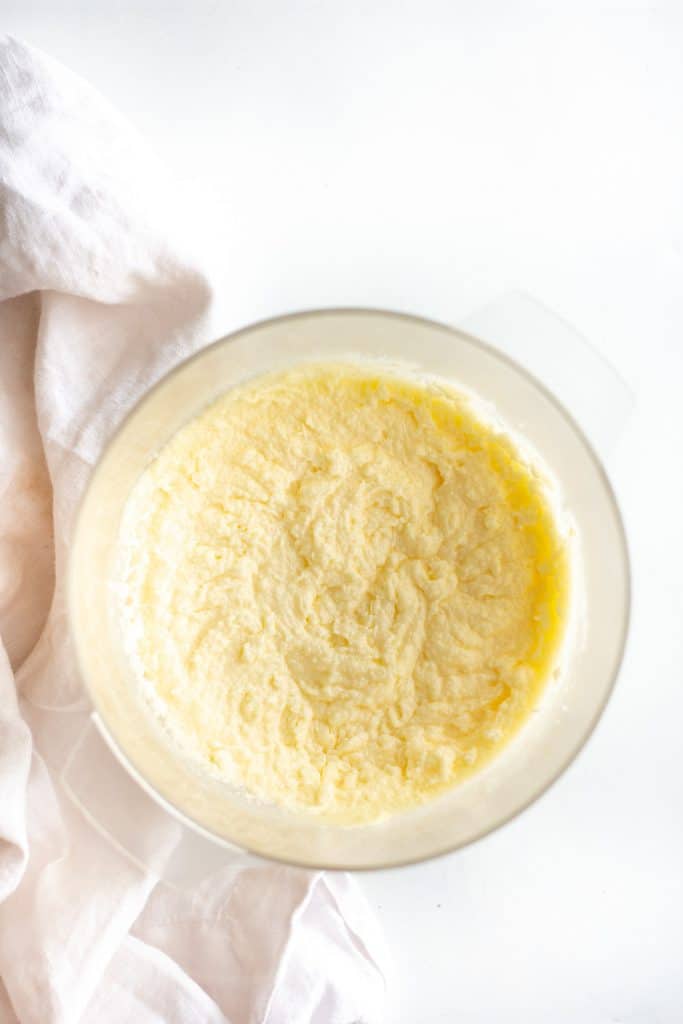 sugar and butter creamed together in a large glass bowl on white background. 