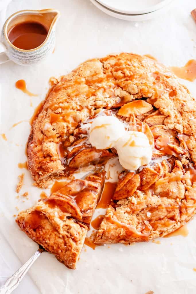 slice of apple galette with caramel and ice cream on white background