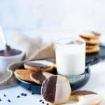 black and white cookies on plate with glass of milk