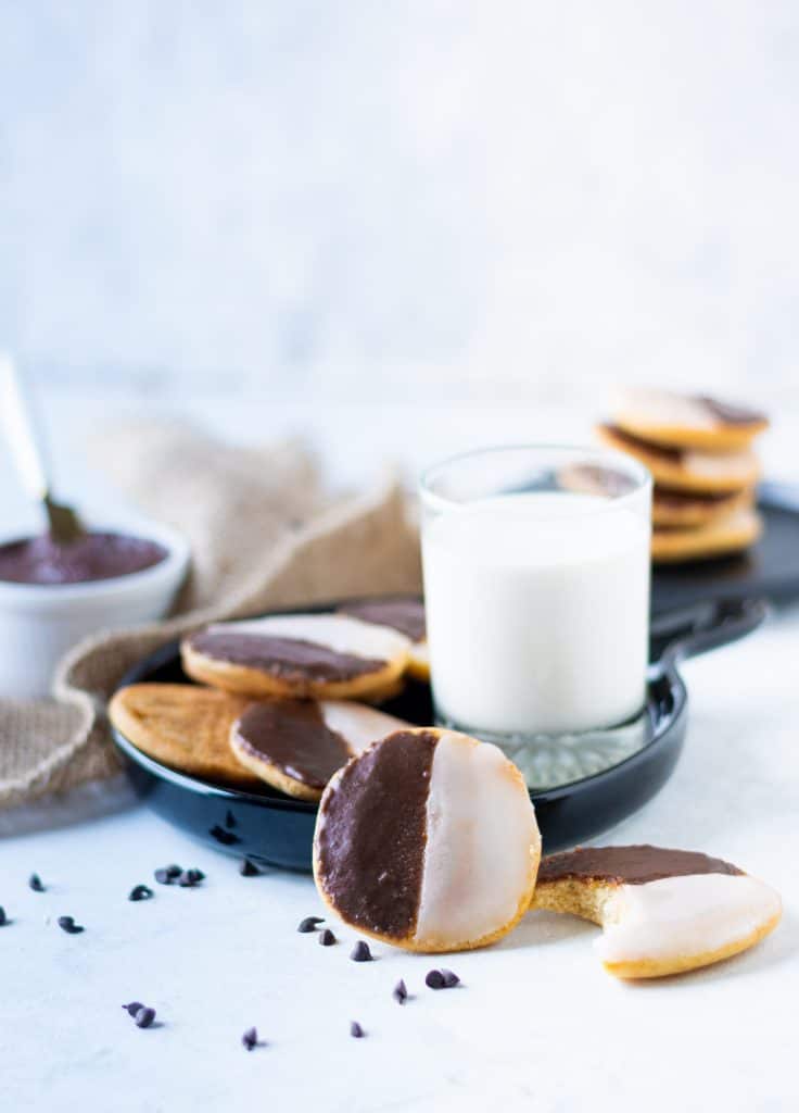 black and white cookies on plate with glass of milk