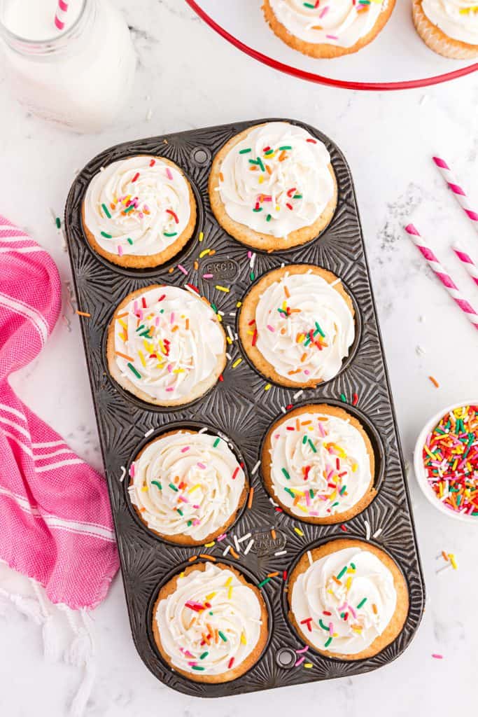 metal cupcake pan with frosted white cupcakes