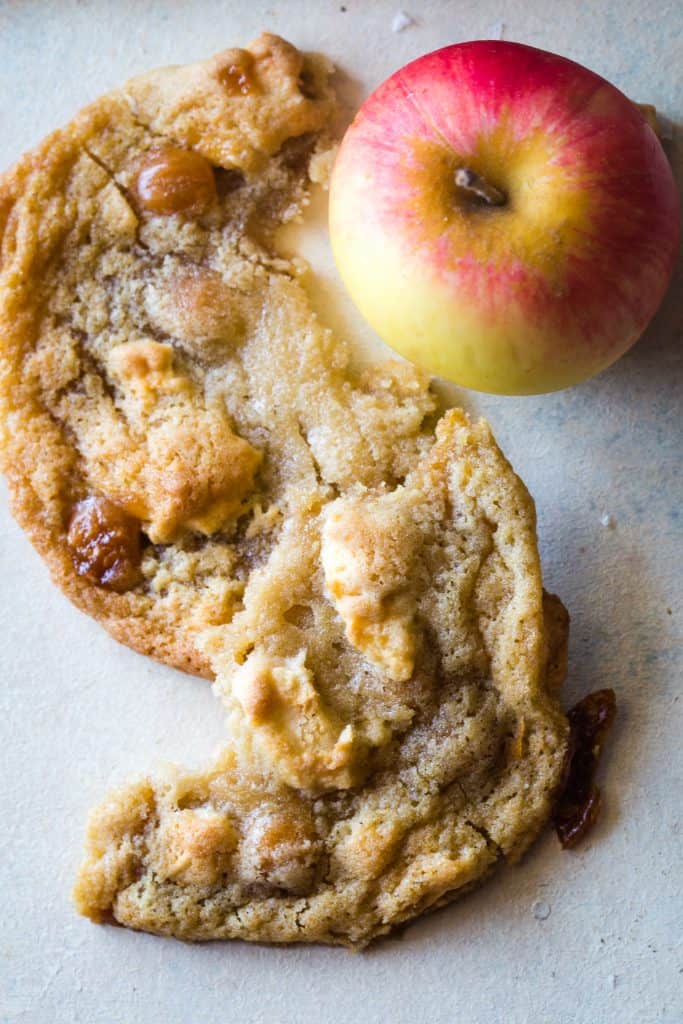 broken caramel apple cookie with whole apple next to it