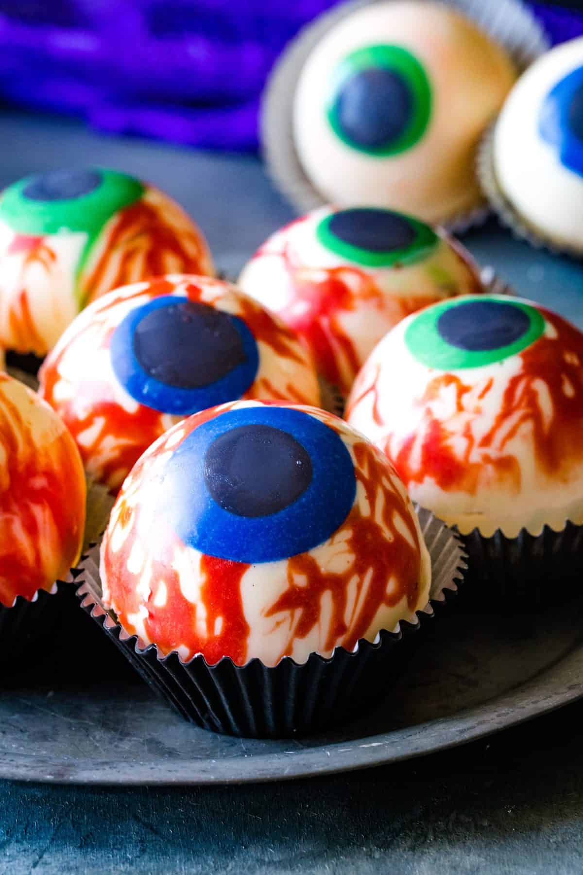 silver plate with halloween eye cocoa bombs in muffin cups.