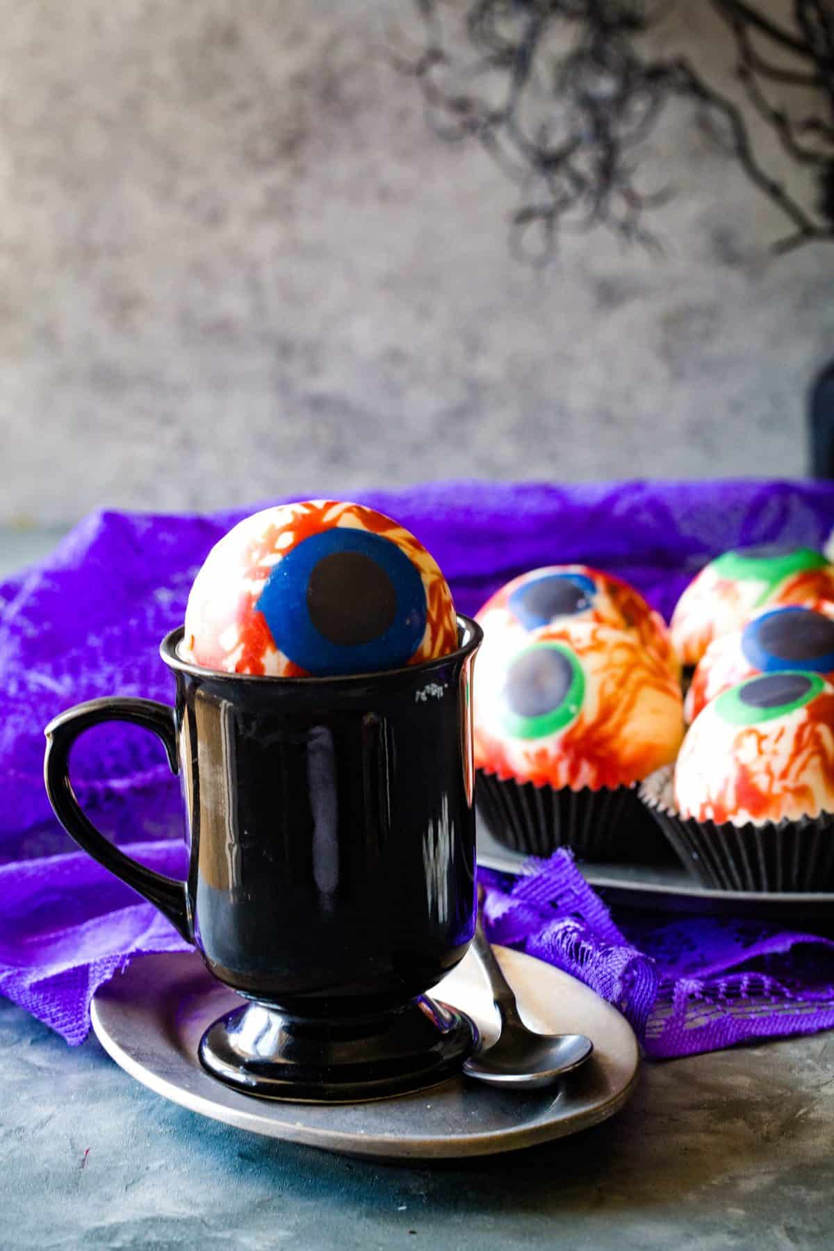 Black mug on silver plate with melting cocoa bomb on top. 