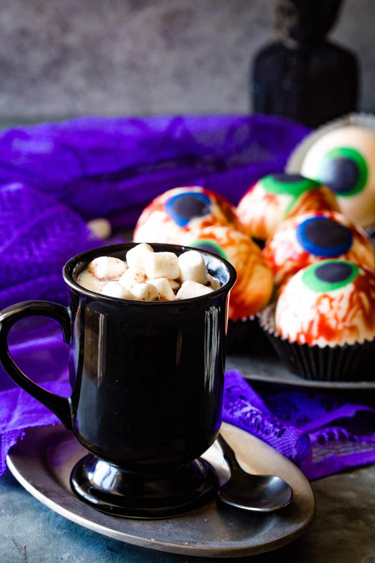 black mug on silver plate with hot chocolate and mini marshmallows. 