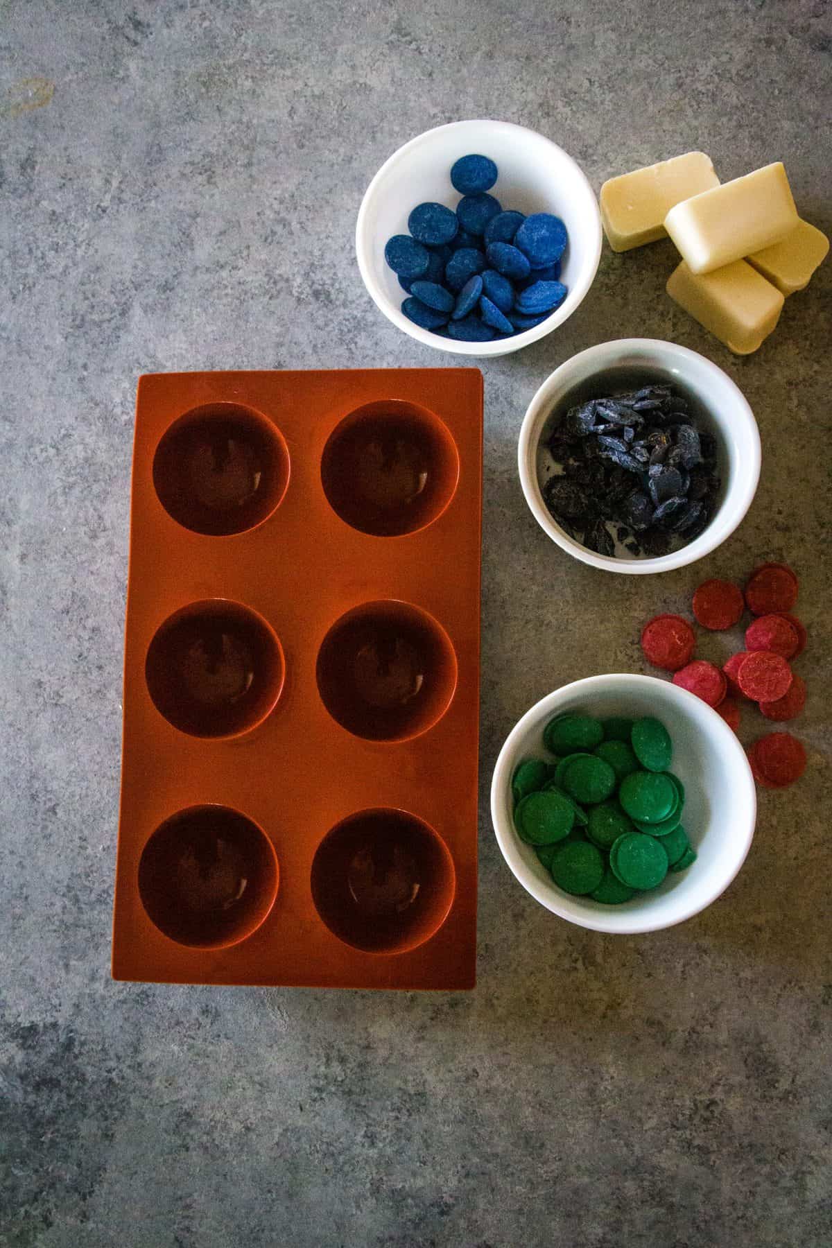 silicone mold with melting chocolate in small bowls on silver background. 