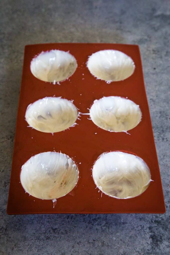 adding white chocolate to spheres in the silicone molds