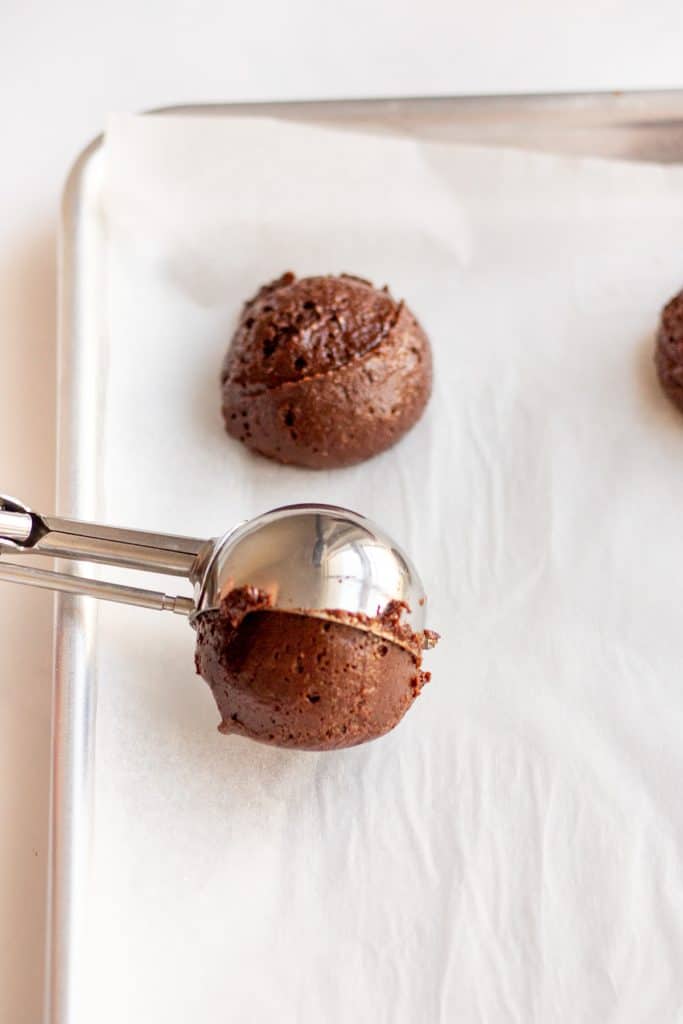 using a cookie scoop to scoop out brownie cookie dough balls