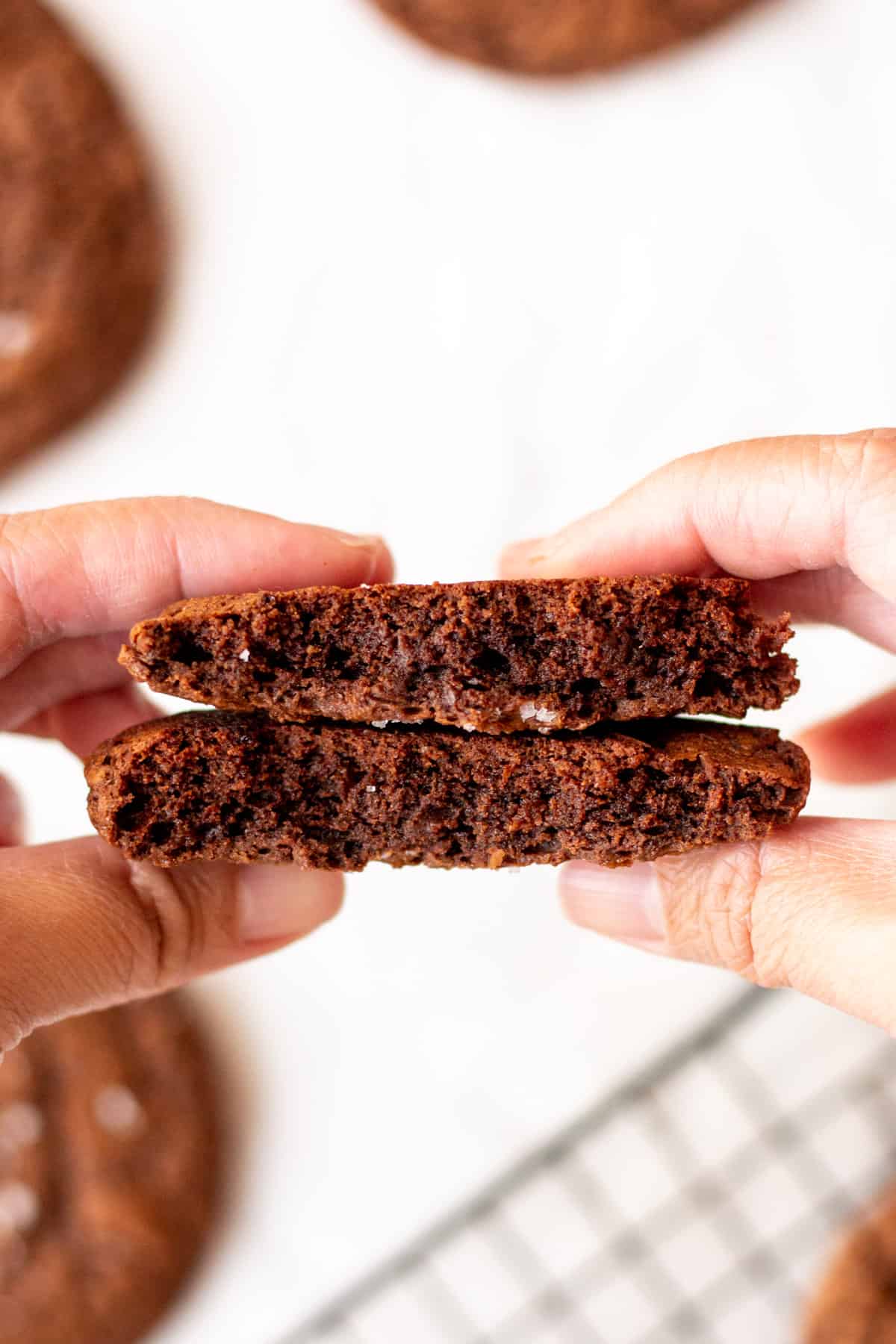 hands holding brownie cookie cut in half