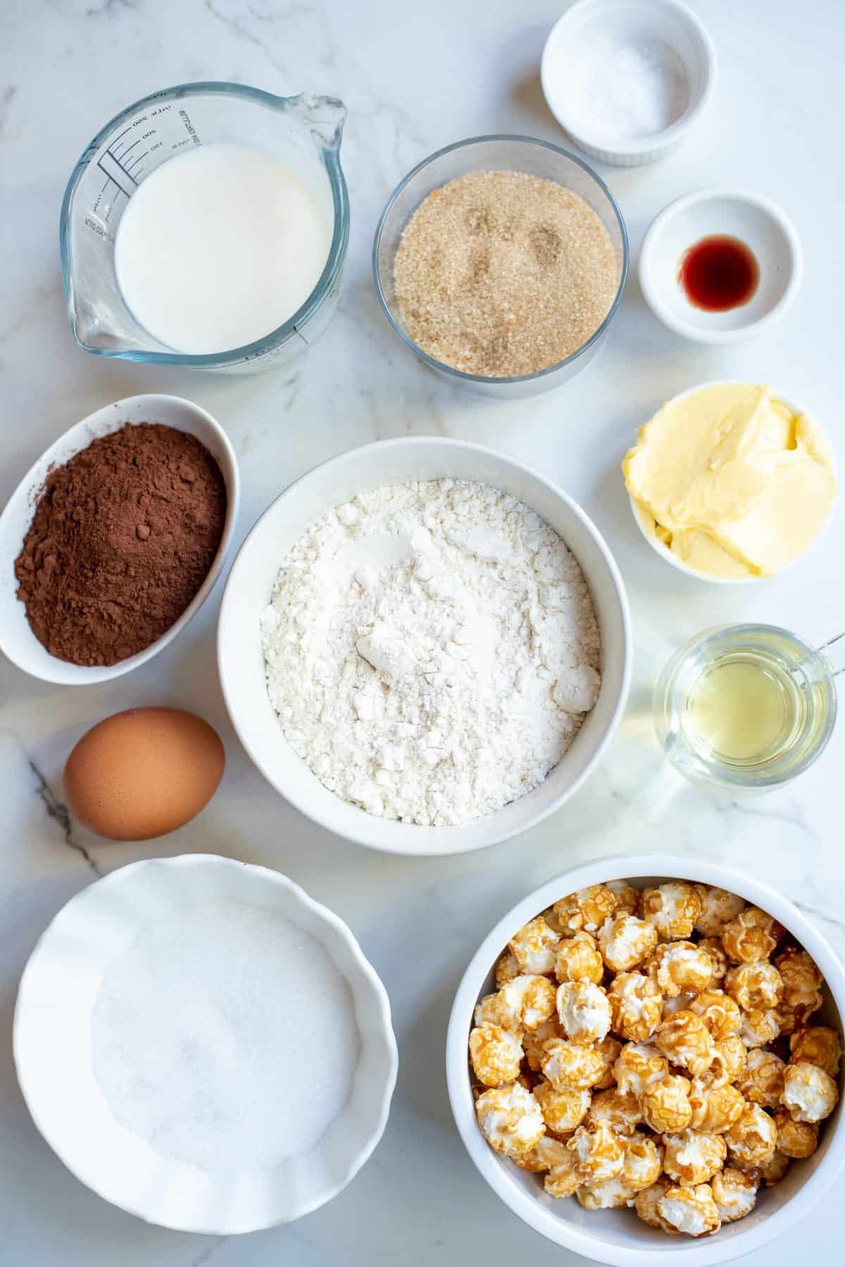 ingredients in white bowls to make chocolate caramel corn cake
