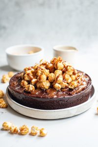 chocolate cake with caramel corn topping and drizzled caramel on white background