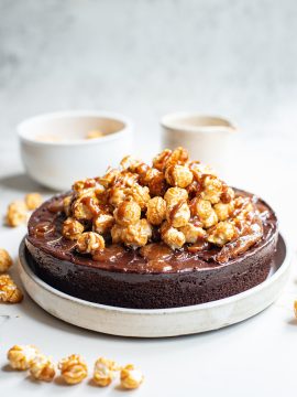 chocolate cake with caramel corn topping and drizzled caramel on white background
