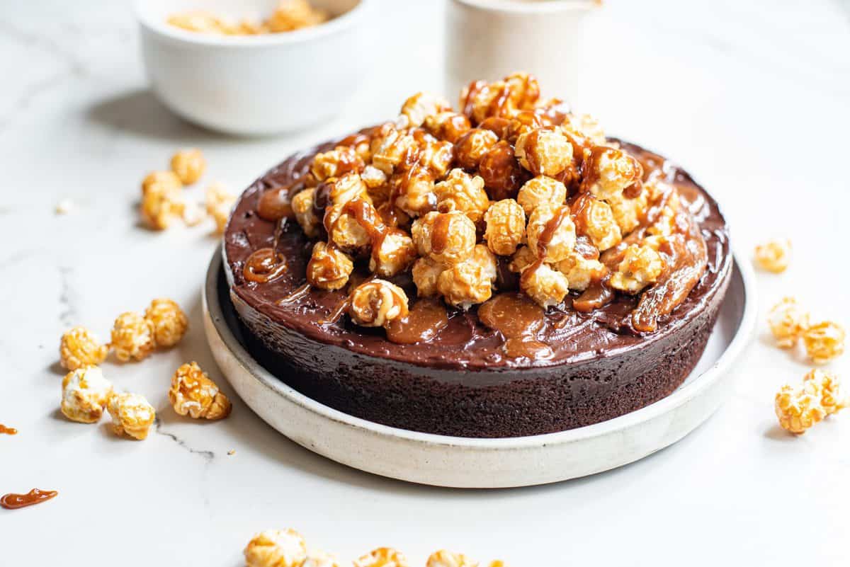 chocolate caramel corn cake on white serving plate on white background
