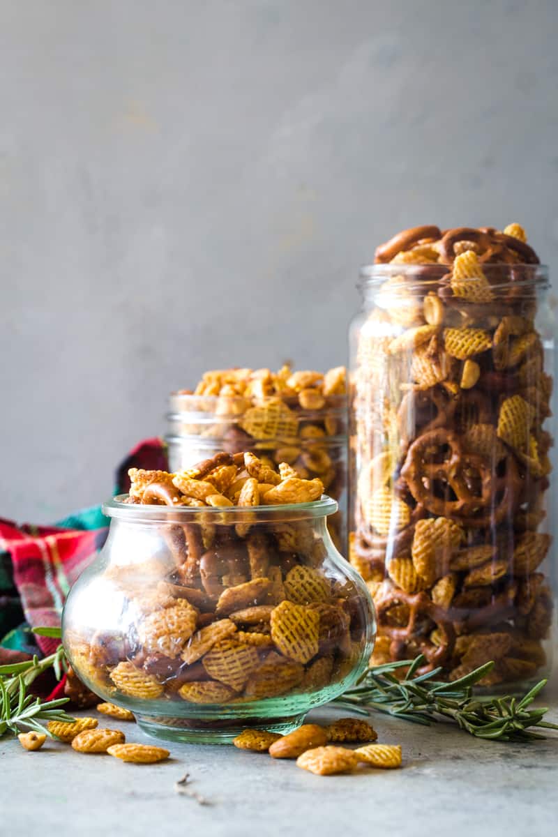 three different sized glass jars filled with rosemary Chex mix