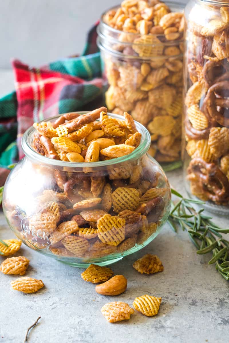 a round week jar filled with rosemary garlic Chex mix on metal background 