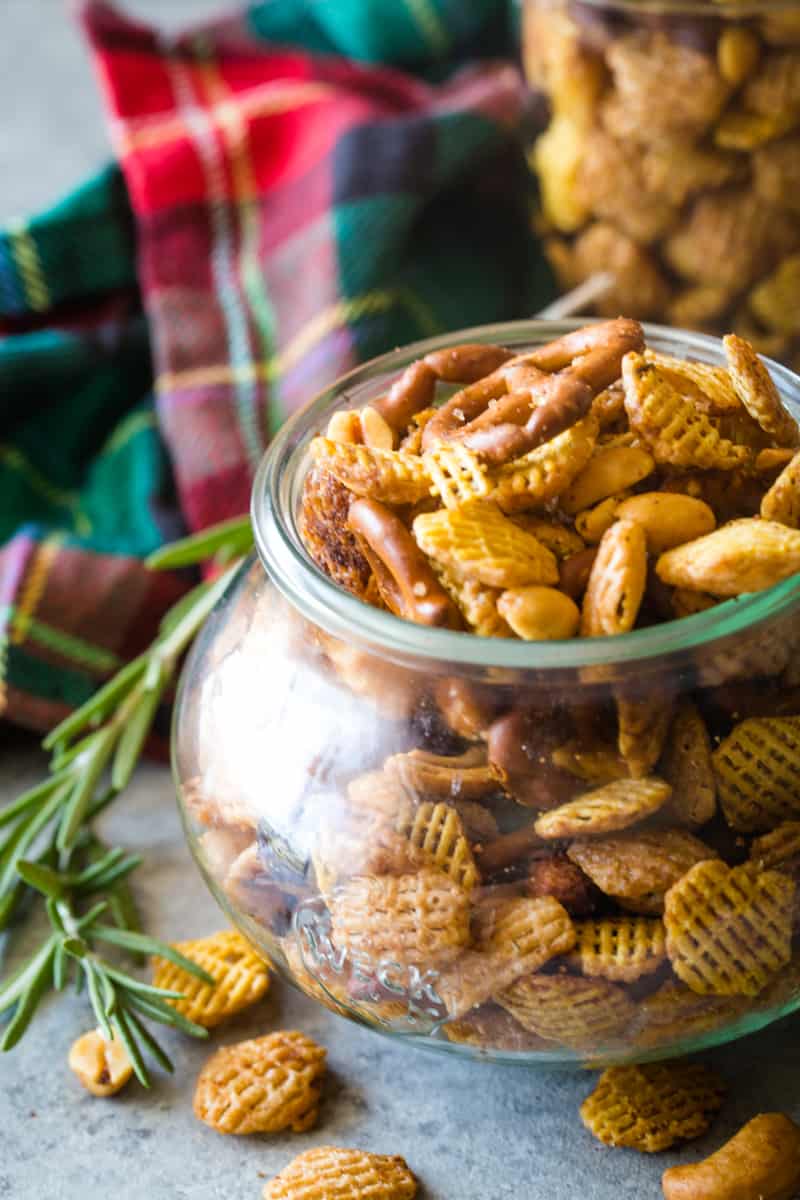 up close photo of jar filled with rosemary Chex mix and red checked dish towel in background