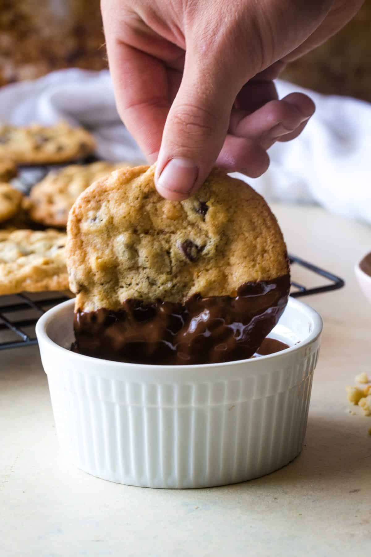 hand dipping cookies in melted chocolate