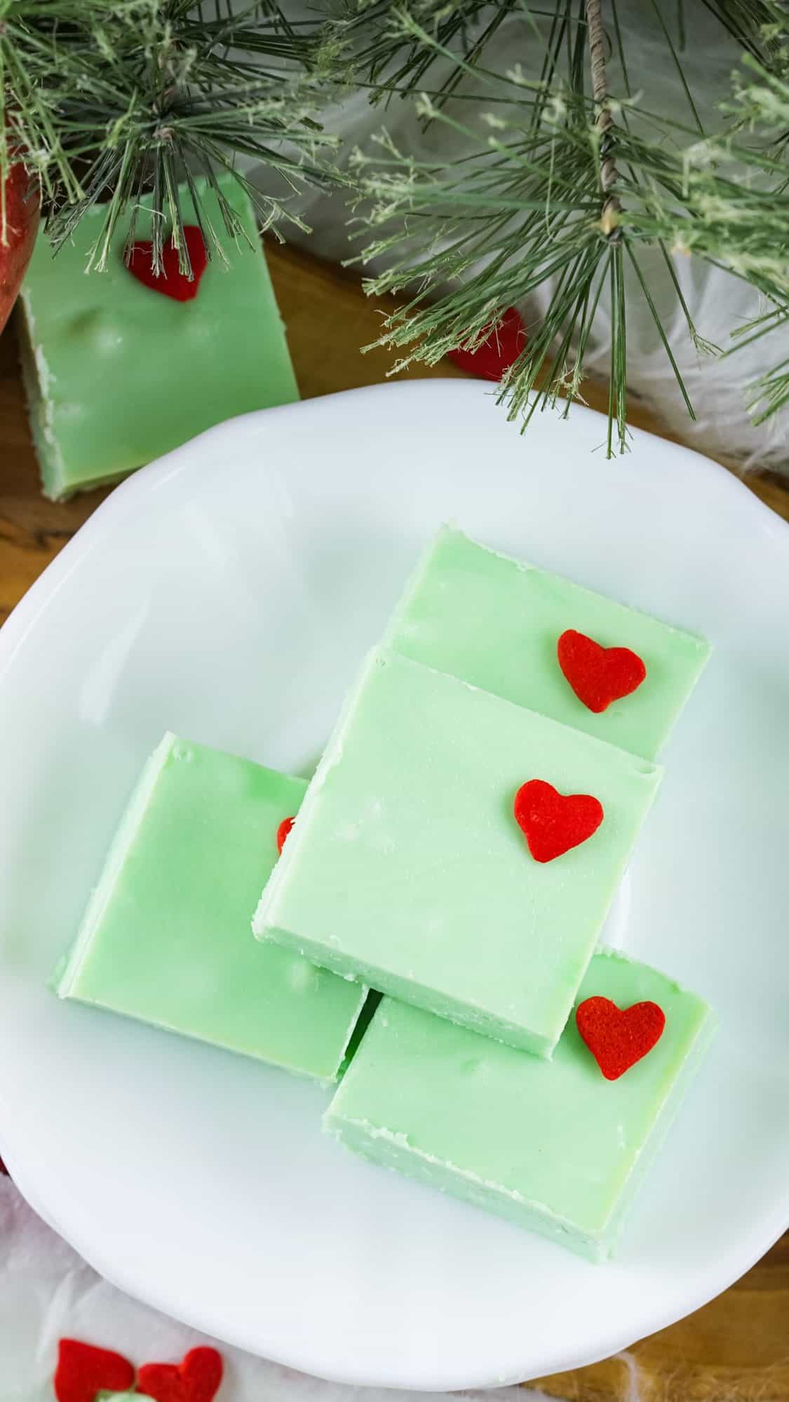 grinch fudge recipe squares on white plate with pine in the background