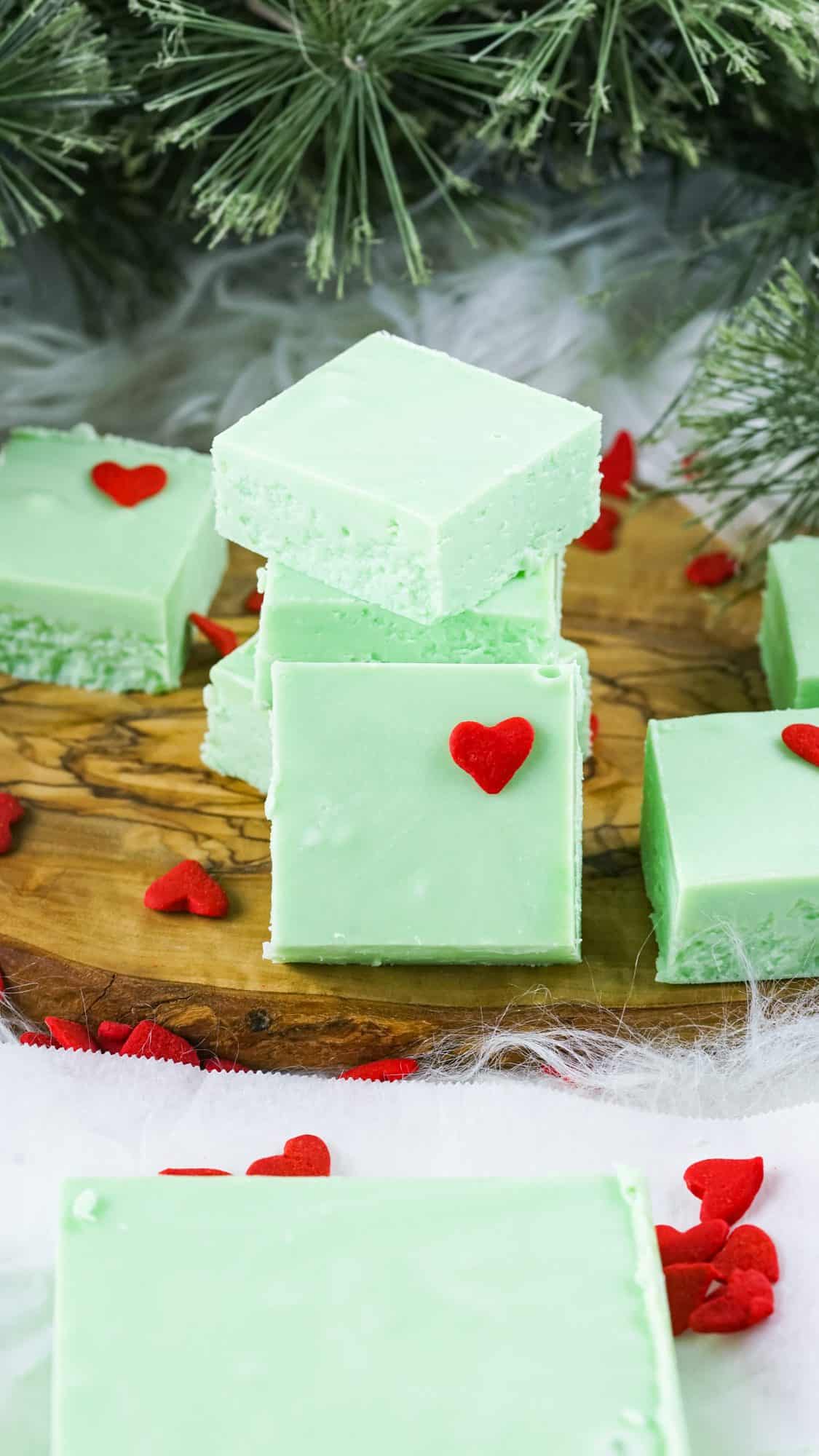 green grinch fudge with red heart standing up on wood cutting board
