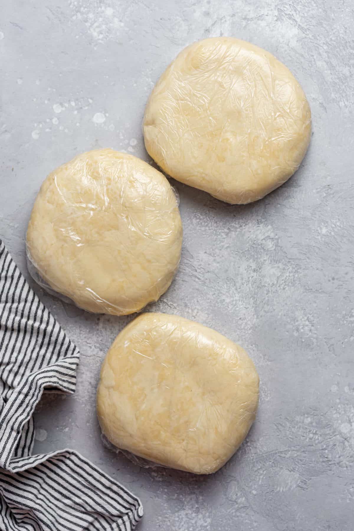 dough formed into 3 disks then wrapped in plastic wrap and chilled