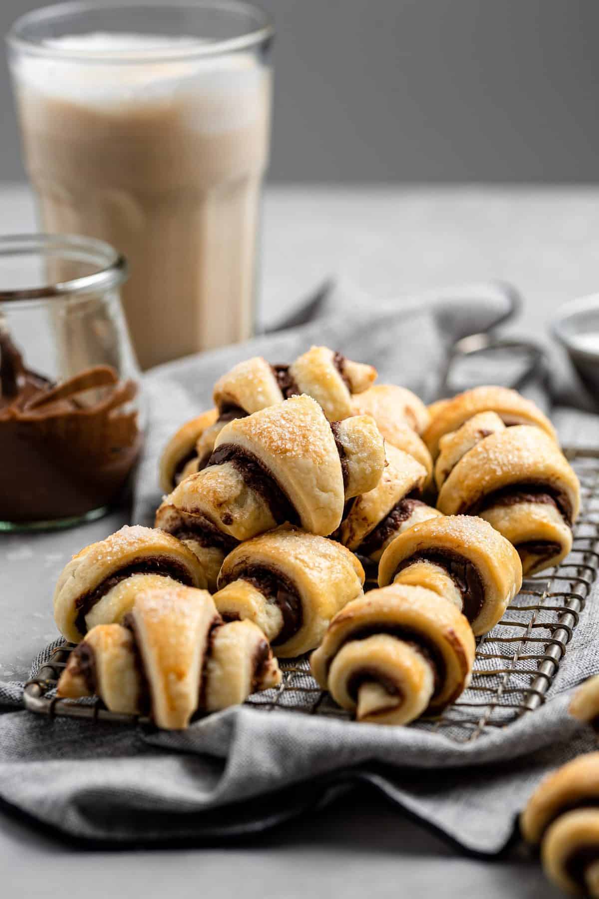 a plate of the best rugelach cookies with strawberry jam and a latte in background