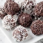 white plate with coconut and chocolate rum balls stacked