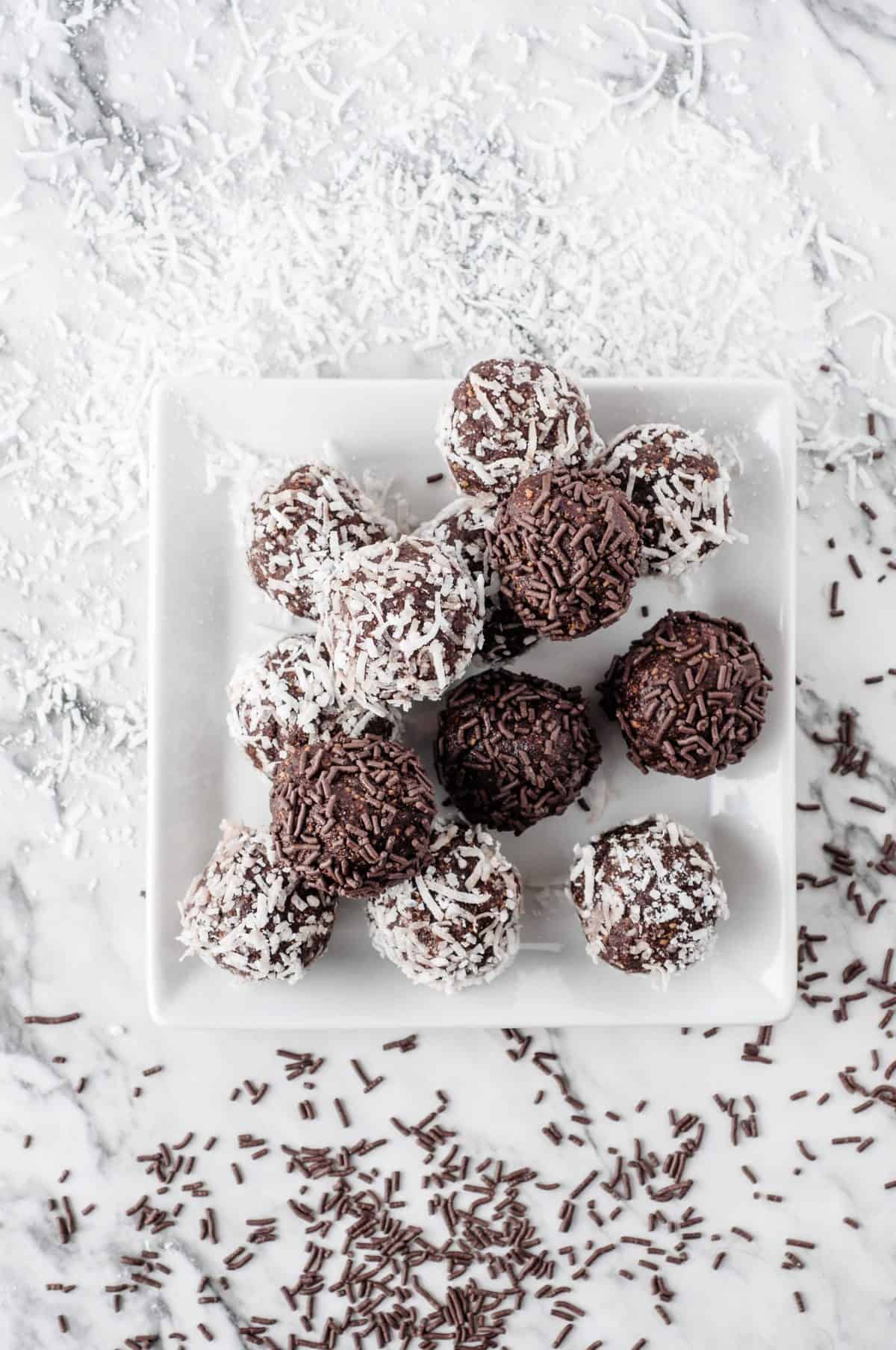 white plate stacked with chocolate rum balls on white background