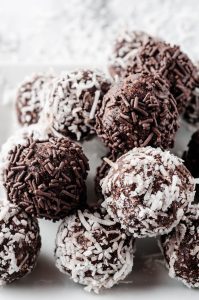 white plate of chocolate rum balls rolled in sprinkles and coconut