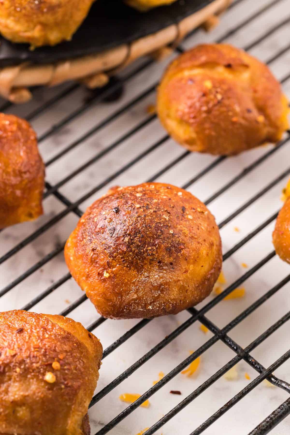 up close photo of the baked stuffed pretzel balls on a black wire cooling rack