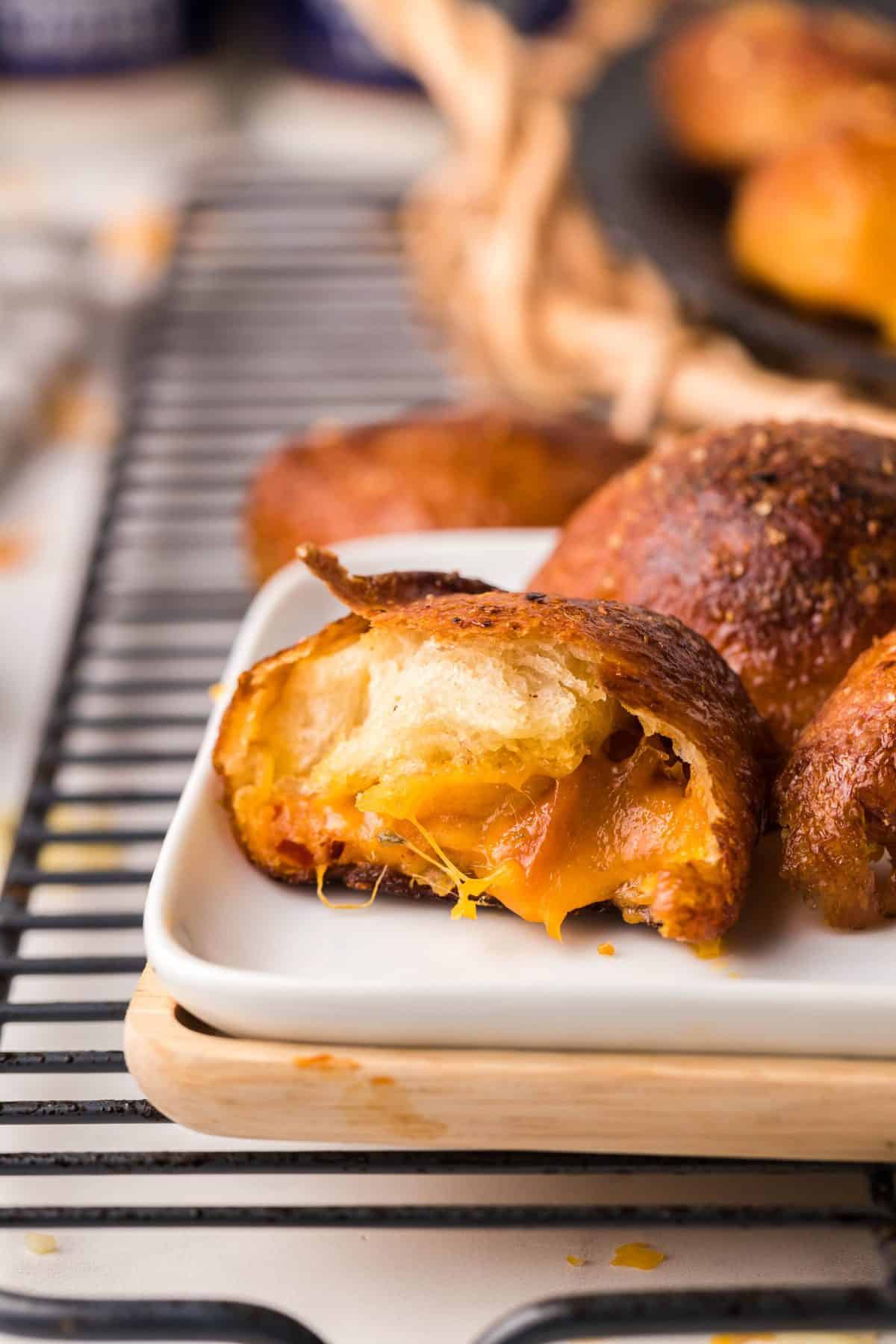 white plate with beer cheese stuffed pretzel roll cut in half to show melty cheese