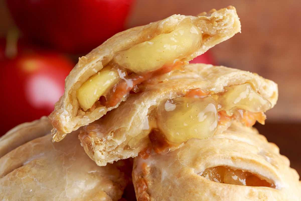 horizontal photo of a caramel apple mini pie cut in half showing the apple filling
