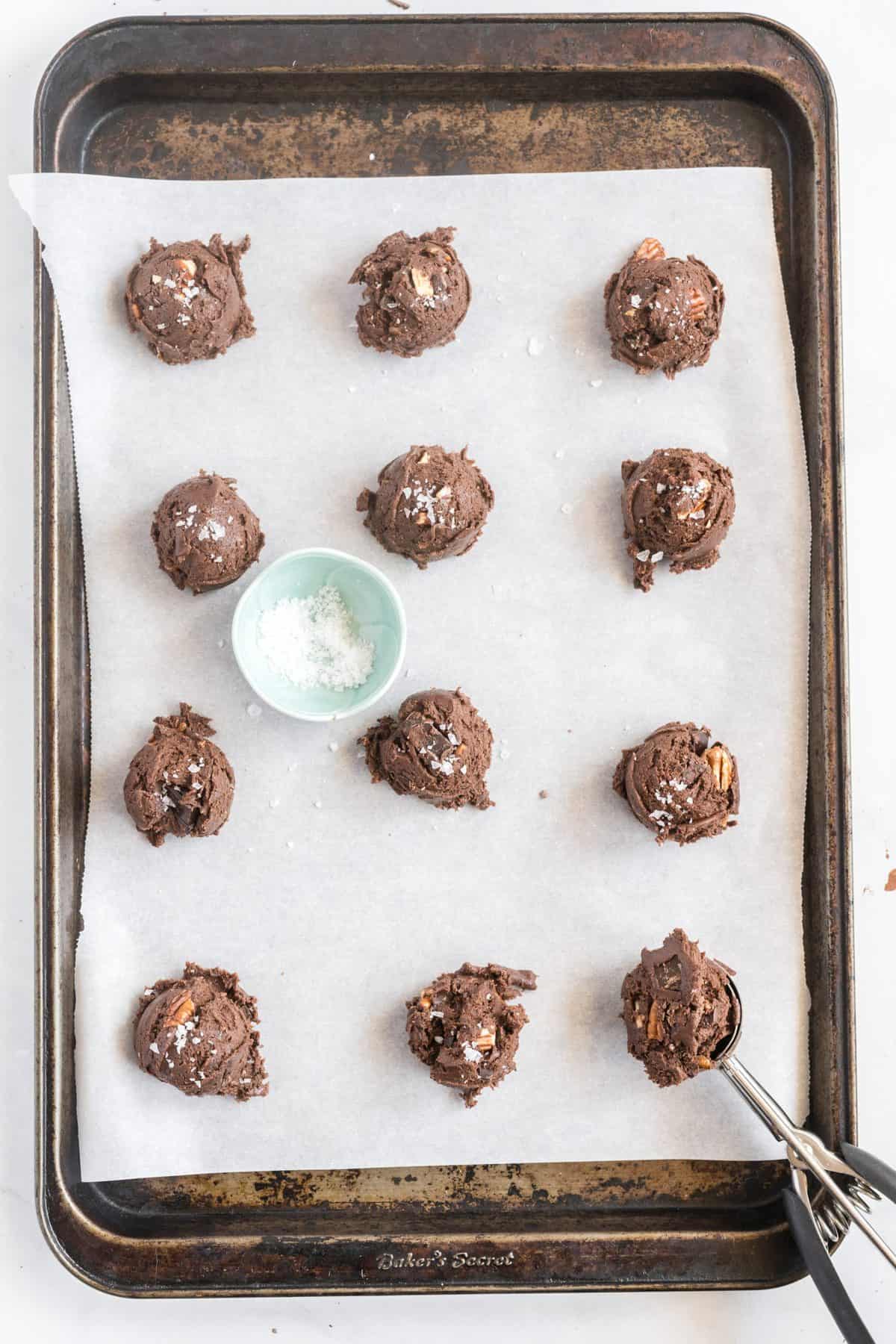 Cookie dough balls scooped out onto a parchment lined cookie sheet. 