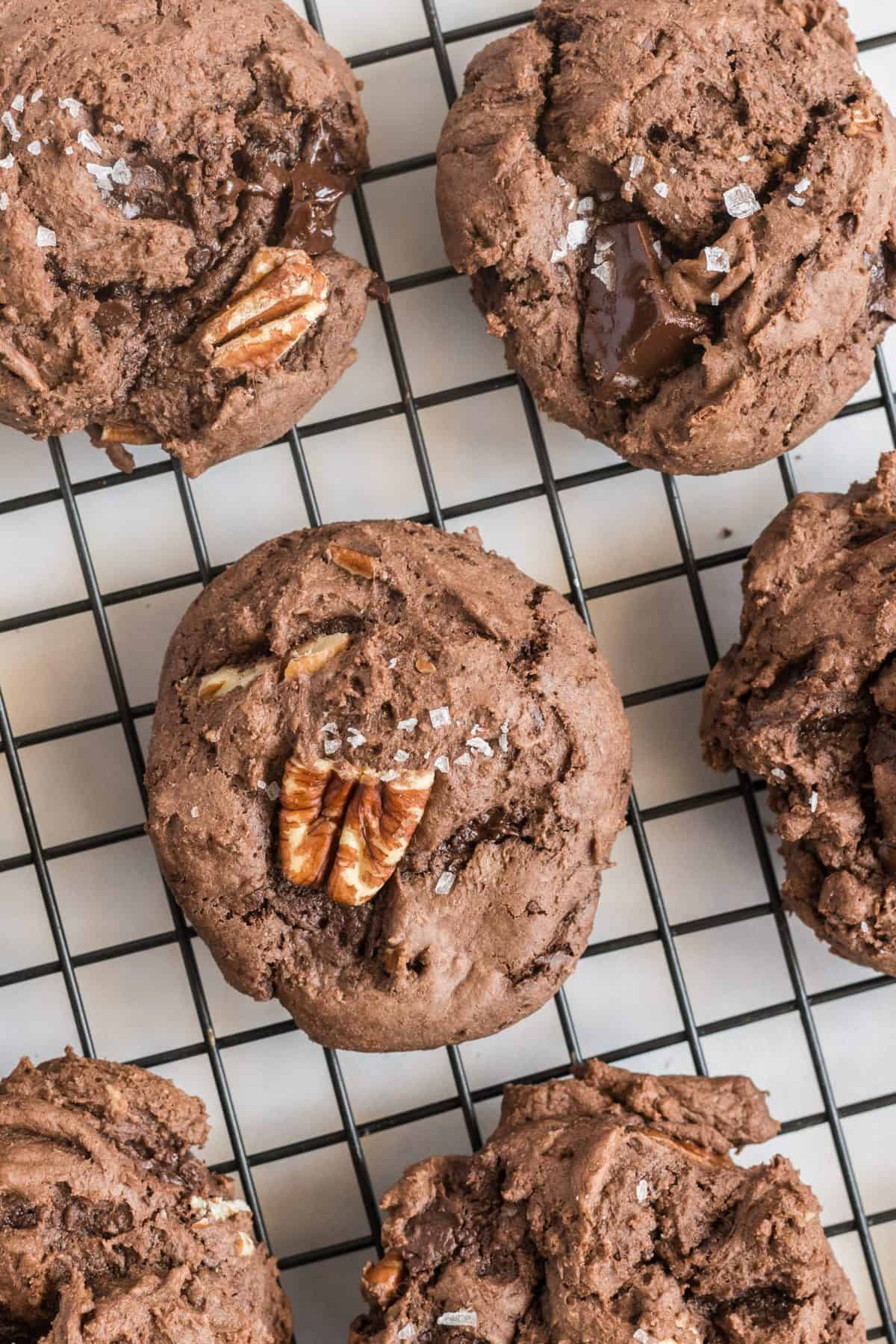 Up close photo of a baked chocolate cake mix cookie topped with pecans and sea salt