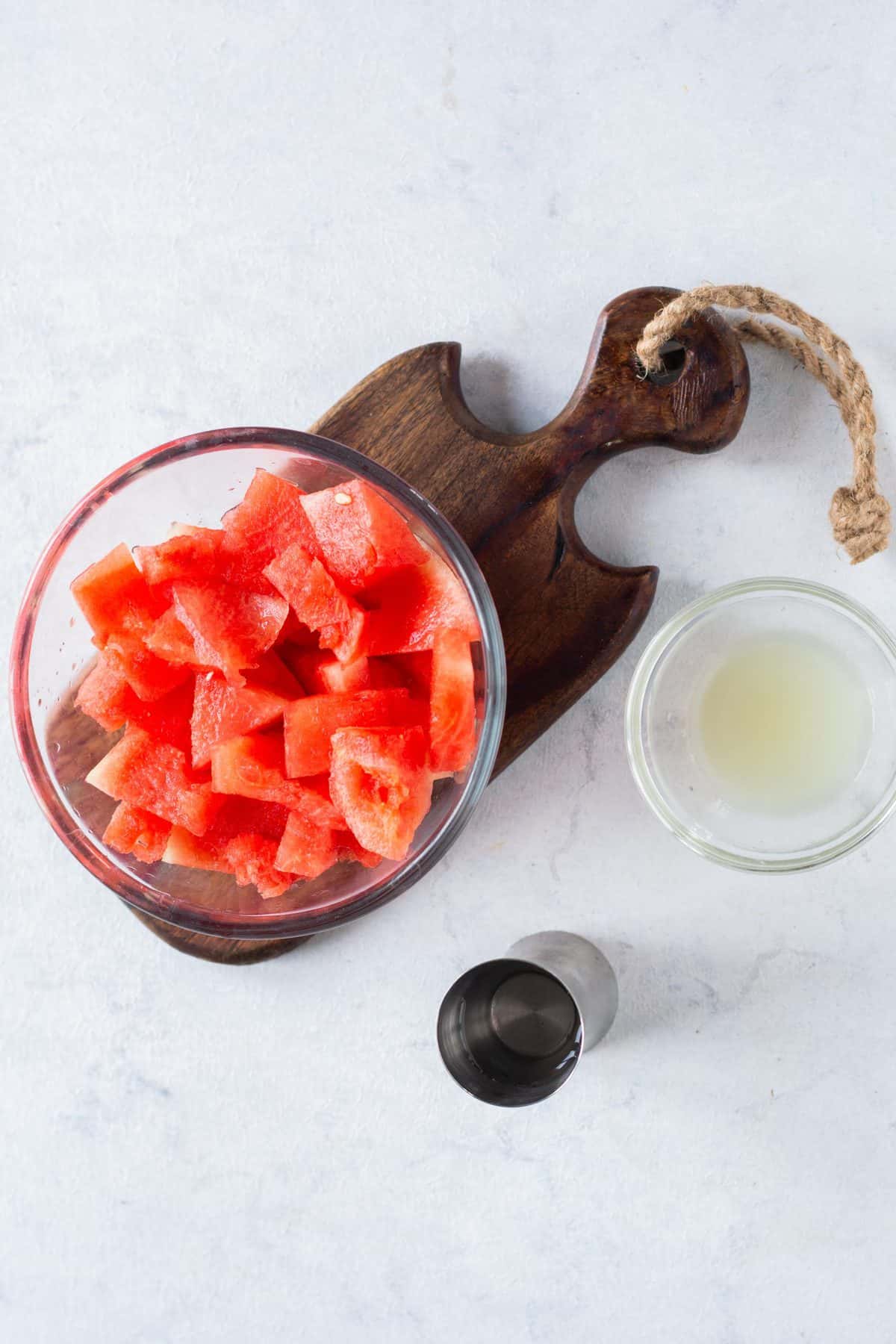 bowl of cut up water melon next to small bowl of lemon juice.